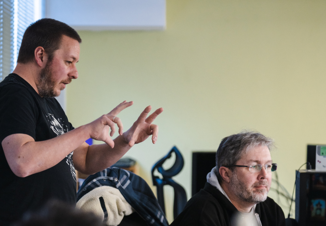 Photo of two Stainless Games team members having a discussion at a computer